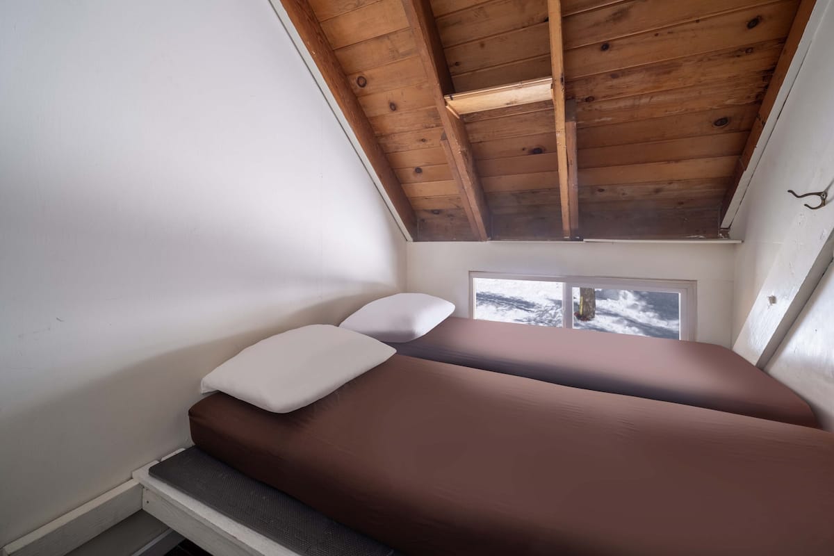 Una habitación pequeña y acogedora con techo inclinado y ventana con vistas al exterior.
