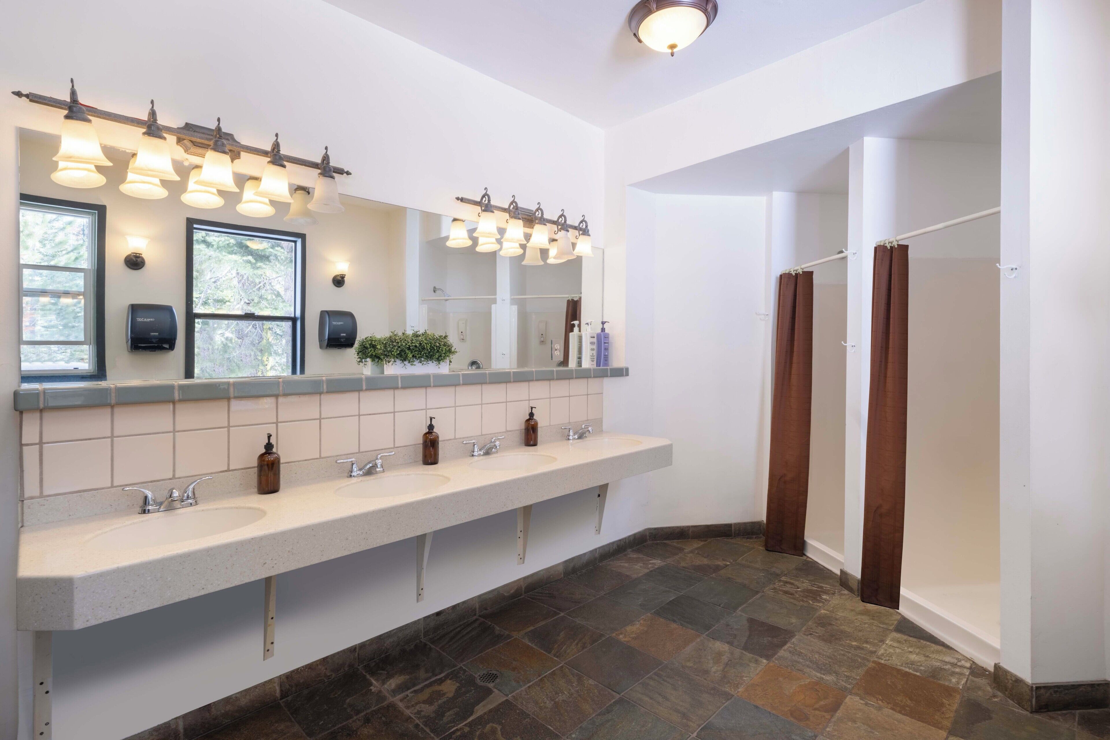 Une salle de bain moderne dotée d’un long meuble-lavabo, de plusieurs vasques et d’un grand miroir.