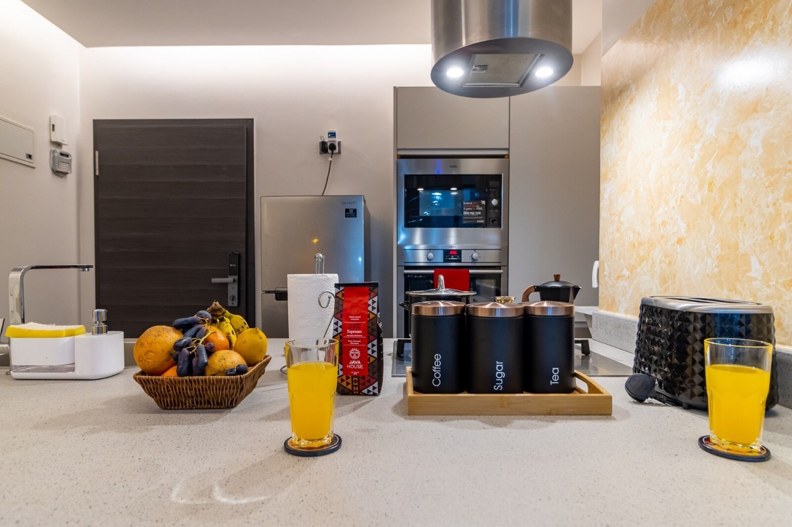 A modern kitchen with a coffee station, a refrigerator, and a microwave.