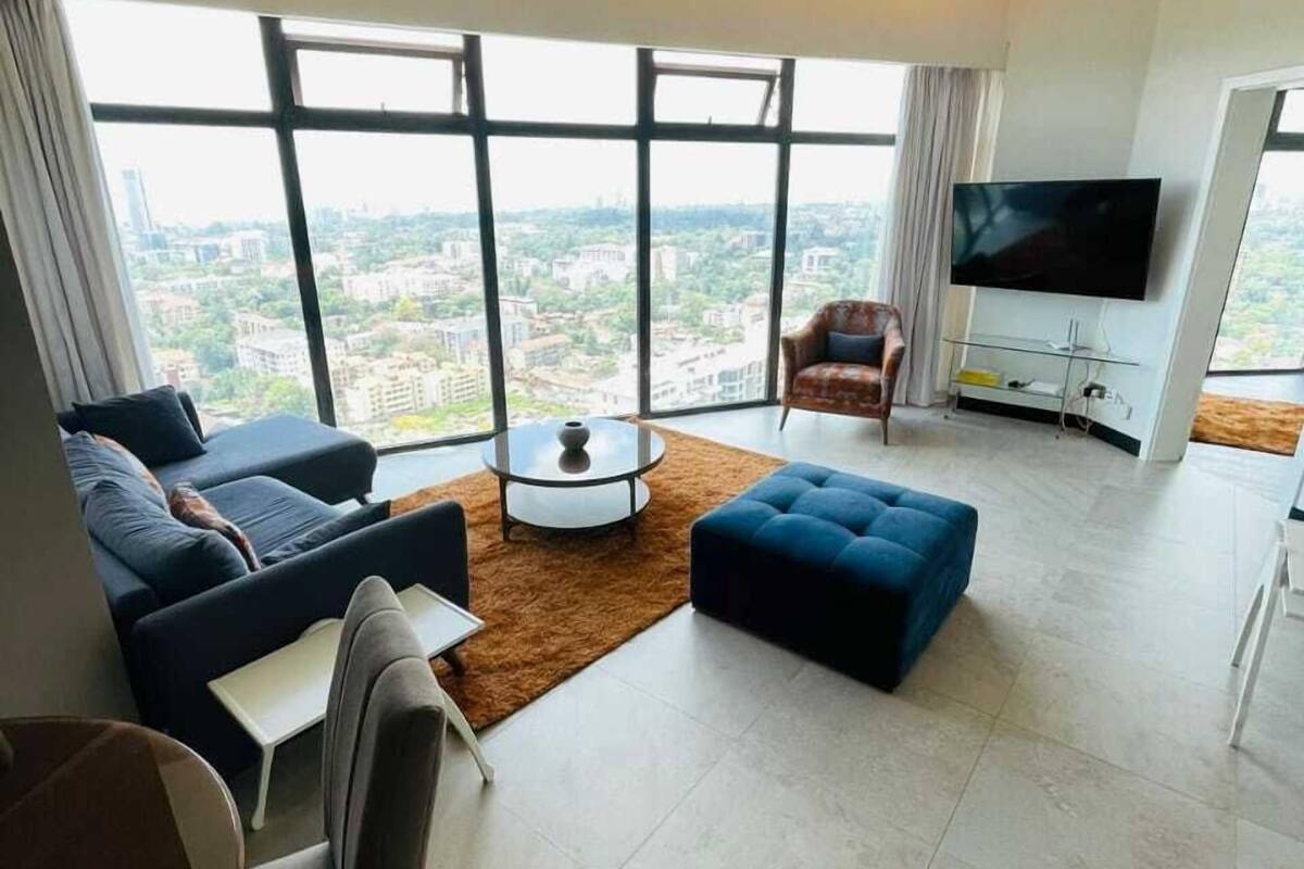 A modern living room with a large window, a flat-screen TV, and a sofa.