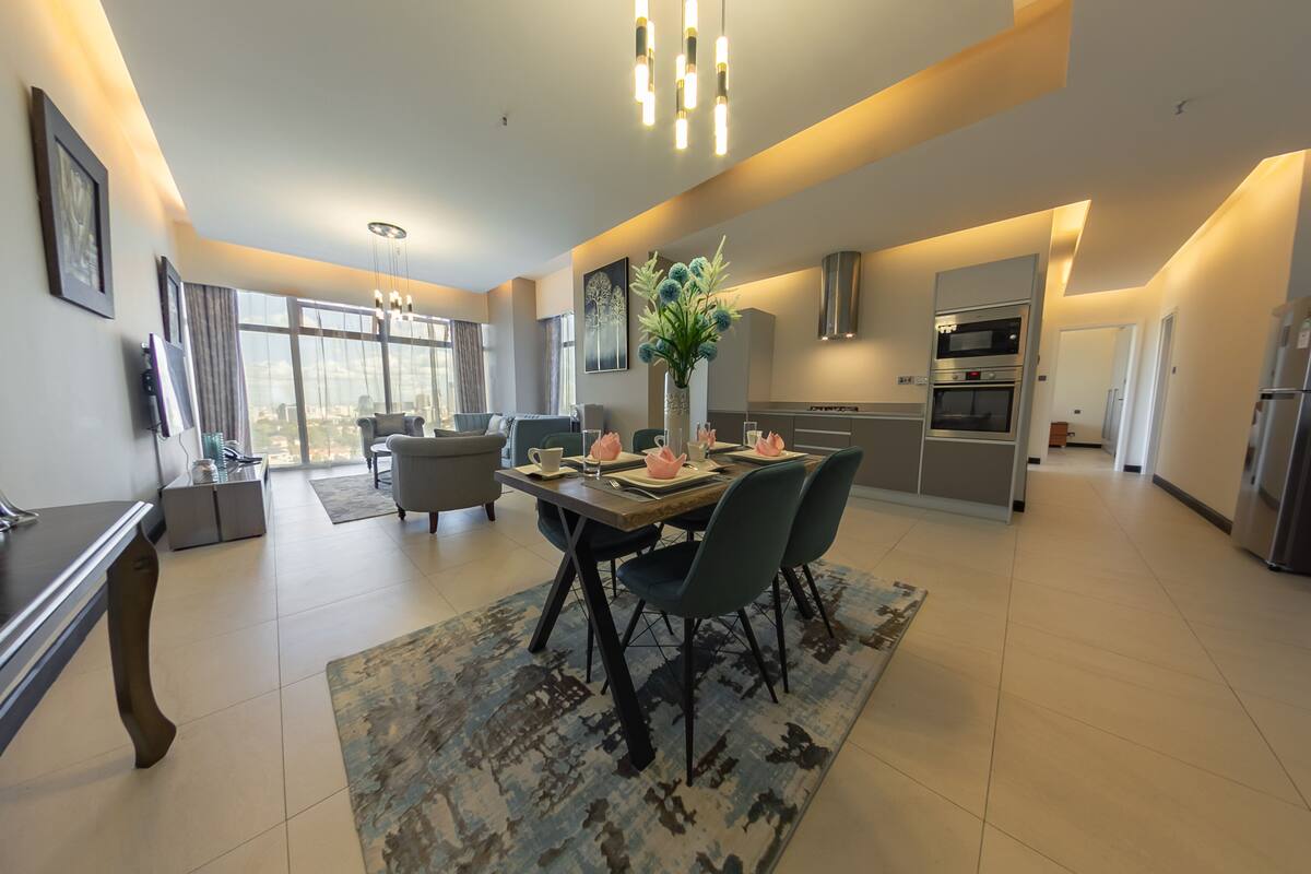 A modern kitchen with a dining area, large windows, and a view of the city.
