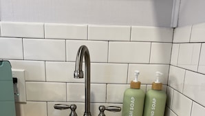Lavello cucina in acciaio inox con rubinetto moderno, due erogatori di sapone e piano di lavoro in legno.