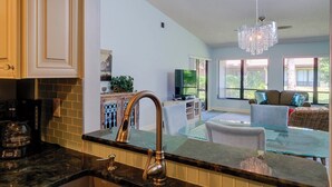 A modern kitchen with a glass island, stainless steel faucet, and a coffee maker.
