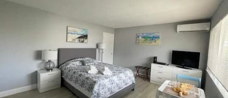 A bedroom with a bed, bedside tables, a TV, and artwork on the walls.