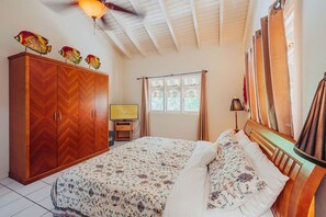 A bedroom with a bed, a wardrobe, a television, and a window with curtains. - 4BR W/Private Pool | Cozy Villa Near Beaches (Aruba)