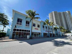A beachfront hotel with a modern design, featuring a prominent 'WINGS' sign, palm trees, and a clear blue sky. - Beach Gear,  Dedicated Workspace, Snorkeling & Surfing (West Palm Beach)