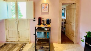 Cocina compacta con estante de madera, cafetera y un cuadro enmarcado en la pared.