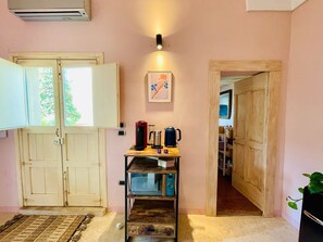 Cocina compacta con estante de madera, cafetera y un cuadro enmarcado en la pared.
