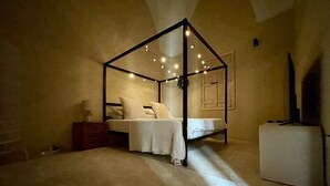 A bedroom with a four-poster bed, a bedside table, and a small white cabinet. - Deluxe 100m² Historic Suite with Private Terrace (San Pietro In Lama)