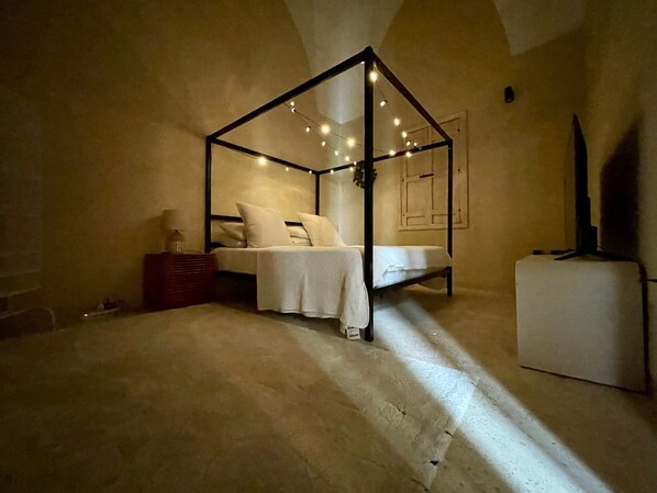 Un dormitorio con una cama con dosel, una mesita de noche y un armario blanco pequeño.