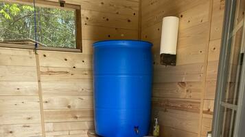 Une petite salle de bain en bois avec un tonneau bleu, un lavabo et une poubelle.