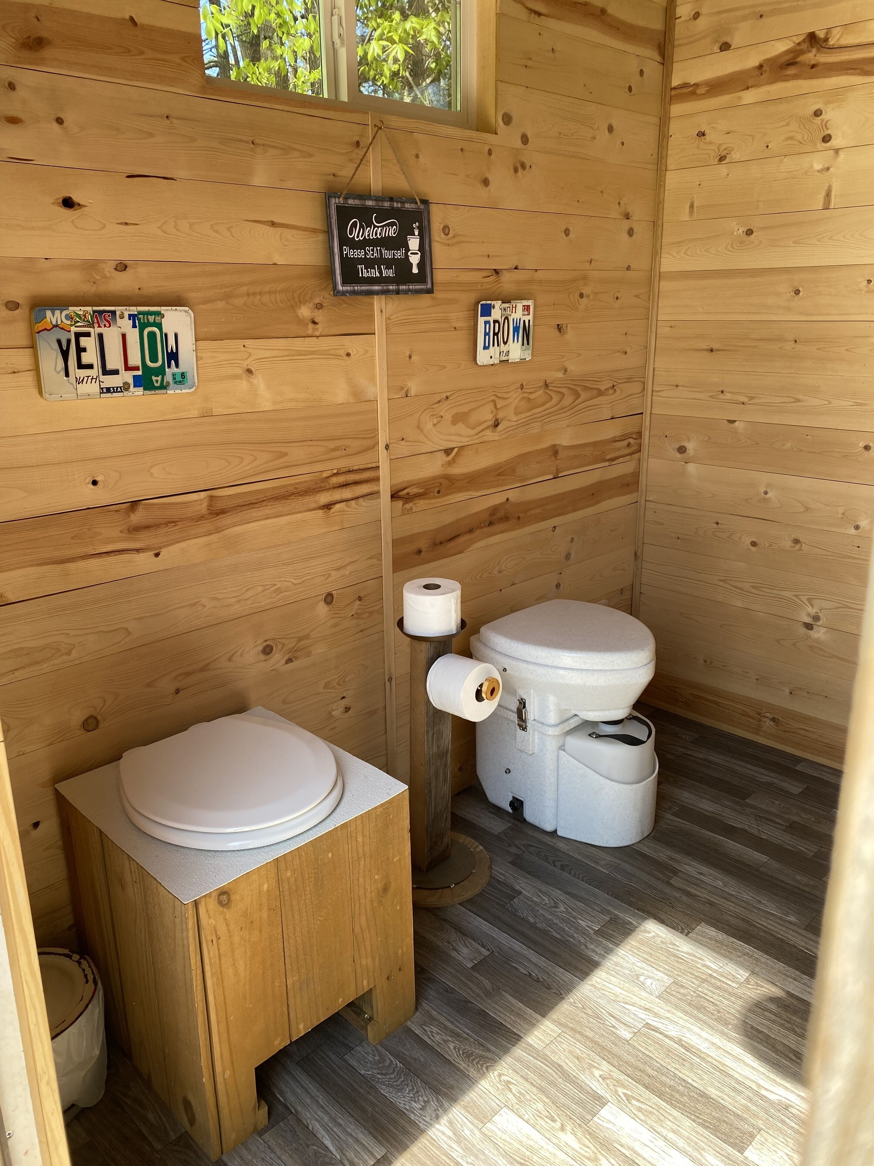Une salle de bain de style rustique, avec des murs en bois, comprenant des toilettes, un bidet et un panneau d’accueil.