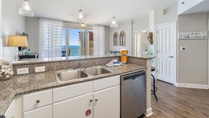 A modern kitchen with granite countertops, stainless steel appliances, and pendant lighting. - Beachfront Master w/balcony access! Shores of Panama (Panama City Beach)