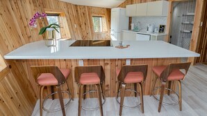 A kitchen with wooden paneling, a central island with bar stools, and a window with natural light.
