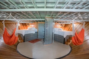 A circular room with two beds, a central divider, and a wooden floor.
