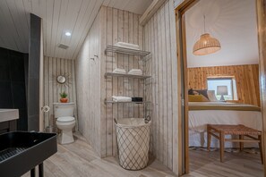 A modern bathroom with a wooden panel design, a toilet, a sink, and a shower area.
