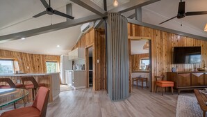 A spacious living area with a high ceiling, wooden paneling, a central glass table, and a seating arrangement.