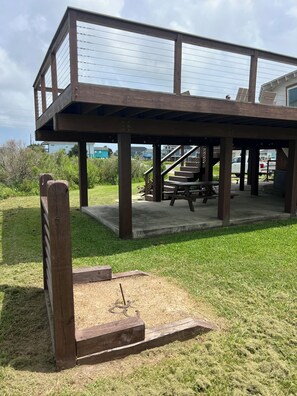 A wooden deck with a picnic table and a staircase leading to a covered area.