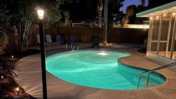 Una piscina de borde curvo, rodeada por una terraza y una valla de madera.