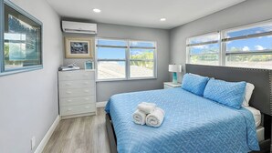 Ein Schlafzimmer mit Bett, Nachttisch, Schminktisch und einem Fenster mit Blick.