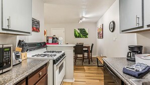 A modern kitchen with white cabinets, a gas stove, a microwave, and a coffee maker.