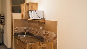Cocina compacta con una isla de madera, un lavamanos empotrado y un comedor con dos sillas de madera.