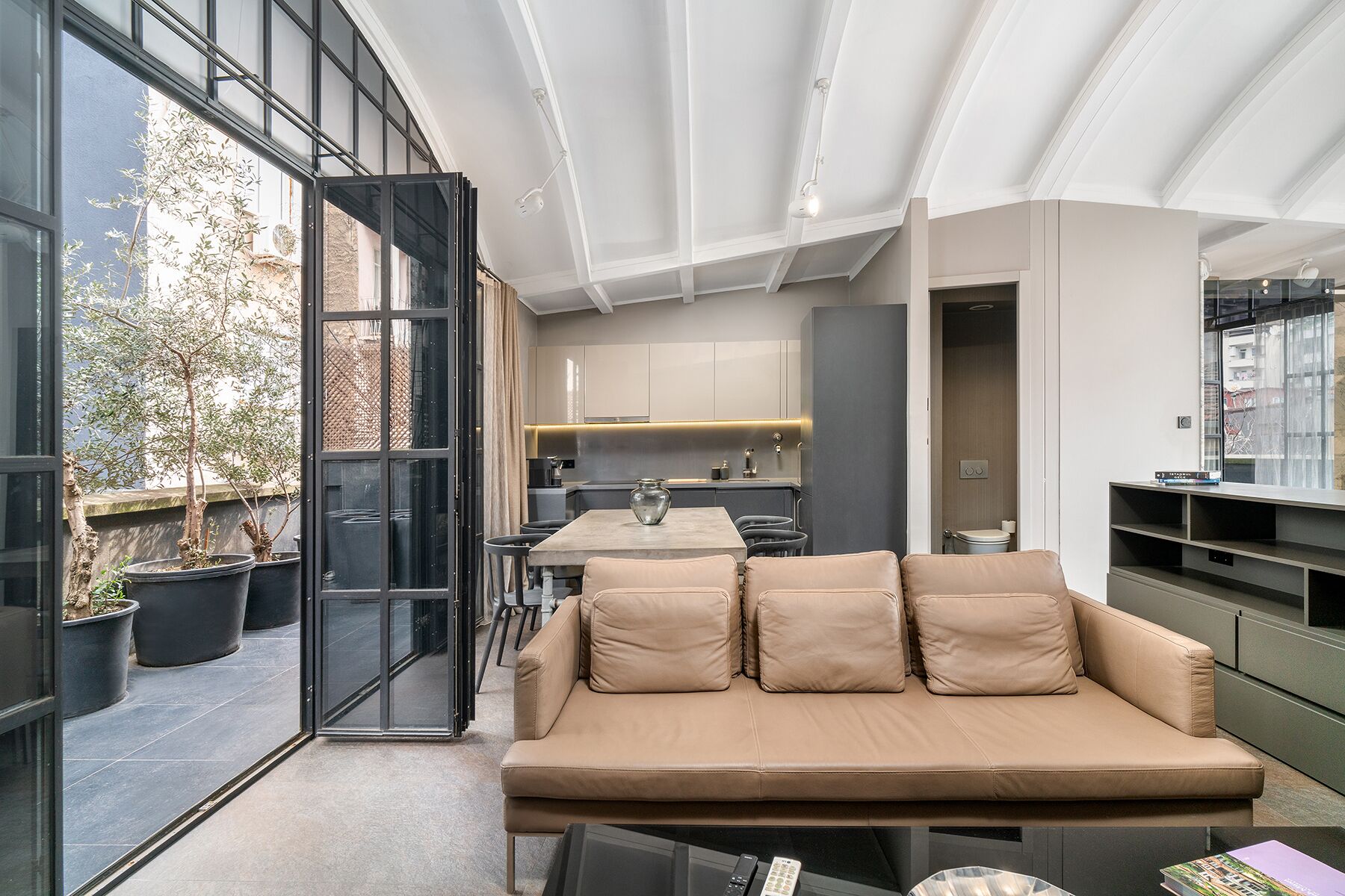 Een modern interieur met een bank, een eettafel en een keukenhoek.