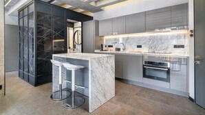 A modern kitchen with a marble island, stainless steel appliances, and a minimalist design. - RA Apartments (Istanbul)