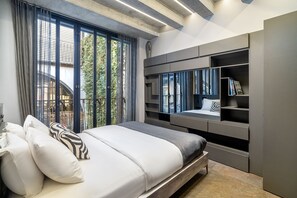 Une chambre moderne avec un grand lit, des étagères intégrées et une vue sur l’extérieur.