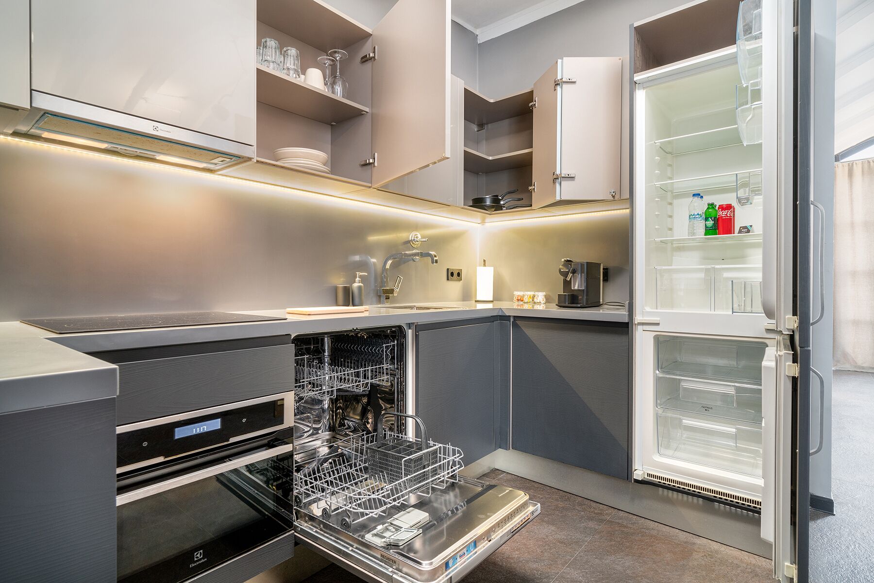 A compact kitchen with a dishwasher, oven, and a refrigerator with a freezer compartment.