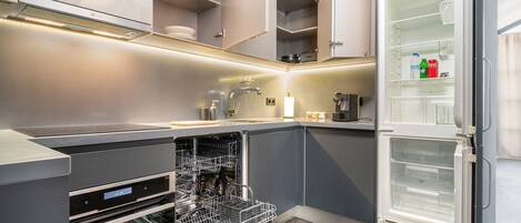A compact kitchen with a dishwasher, oven, and a refrigerator with a freezer compartment.