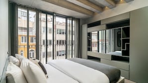 A modern bedroom with a large bed, a built-in wardrobe, and a view of the city through floor-to-ceiling windows. - RA Apartments (Istanbul)
