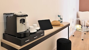 A modern kitchenette with a coffee maker, a laptop, and a tablet on a counter. - Ponte di Tappia Suites (Naples)