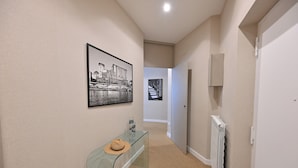 A hallway with a glass console table, a framed picture, and a radiator. - Ponte di Tappia Suites (Naples)