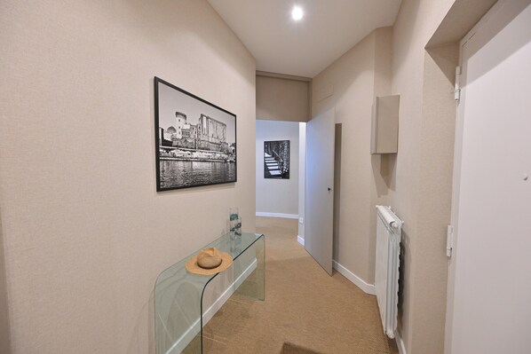 A hallway with a glass console table, a framed picture, and a radiator. - Ponte di Tappia Suites (Naples)