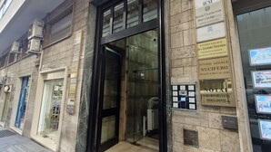 A building with a glass entrance, multiple business signs, and a tiled ground. - Ponte di Tappia Suites (Naples)