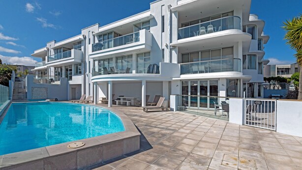 A modern multi-story building with a swimming pool, outdoor seating, and a gated entrance. - Waimahana 5 - Taupo Holiday Apartment (Taupo)