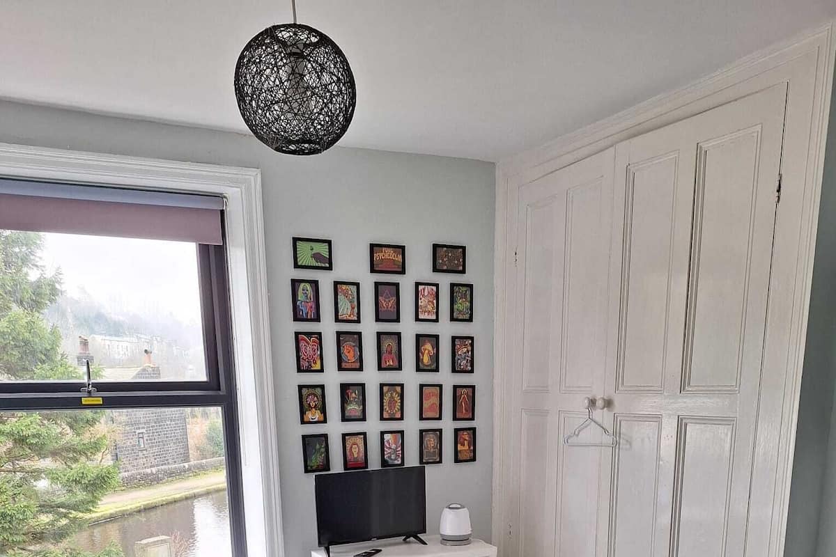 Une chambre à coucher avec un lit, une fenêtre, une armoire et une étagère avec des photos.