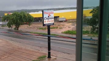 Placa indicando um local chamado 'Pousada Chapada do Araripe', com vista para um edifício amarelo e um caminhão ao fundo.
