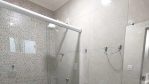 Et badeværelse med bruseniche i glas, toilet og vask med spejl.