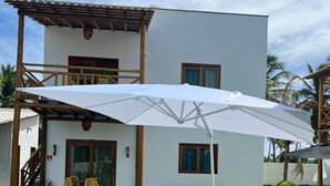 Une maison moderne à deux étages, dotée d’un patio couvert, d’une piscine et d’une pelouse bien entretenue.