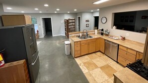 Une cuisine équipée d’un réfrigérateur, d’un évier, d’une cuisinière et de meubles de rangement en bois.