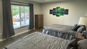 Une chambre d’hôtel avec deux lits, une commode, une lampe et une fenêtre avec des rideaux.