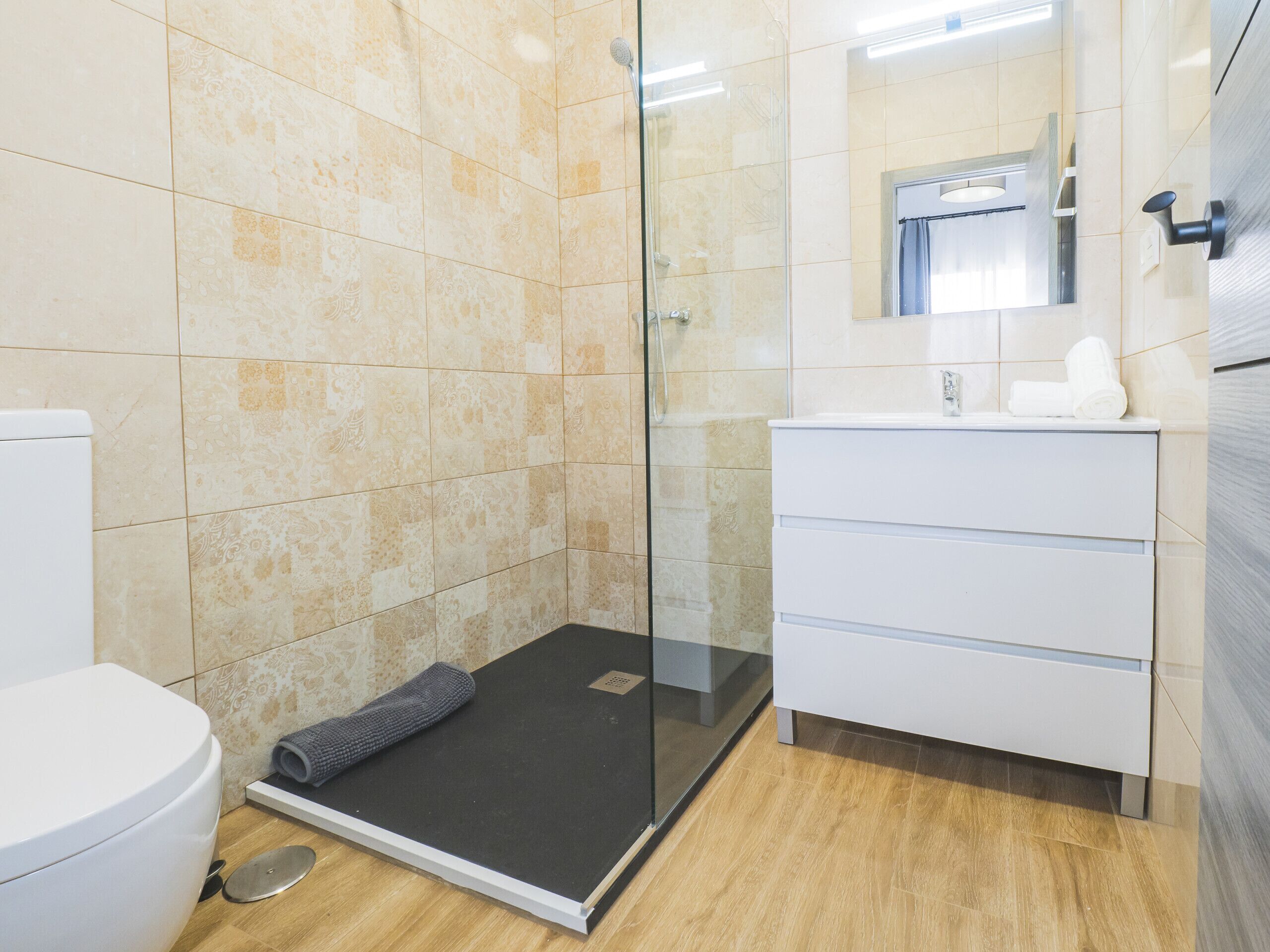 A modern bathroom with a glass shower enclosure, a white sink, and a toilet.