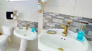 A bathroom with two sinks, one pedestal and one vanity, both with gold faucets. There are two soap dispensers, one blue and one gold. The walls are tiled with a diamond pattern and a section with a brick-like pattern. - Attalia Villa 5-bed in Runaway Bay Near Ocho Rios (Runaway Bay)