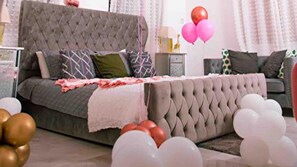 A bedroom with a tufted headboard, a grey sofa, and a bed with a white blanket. There are balloons in the room. - Attalia Villa 5-bed in Runaway Bay Near Ocho Rios (Runaway Bay)
