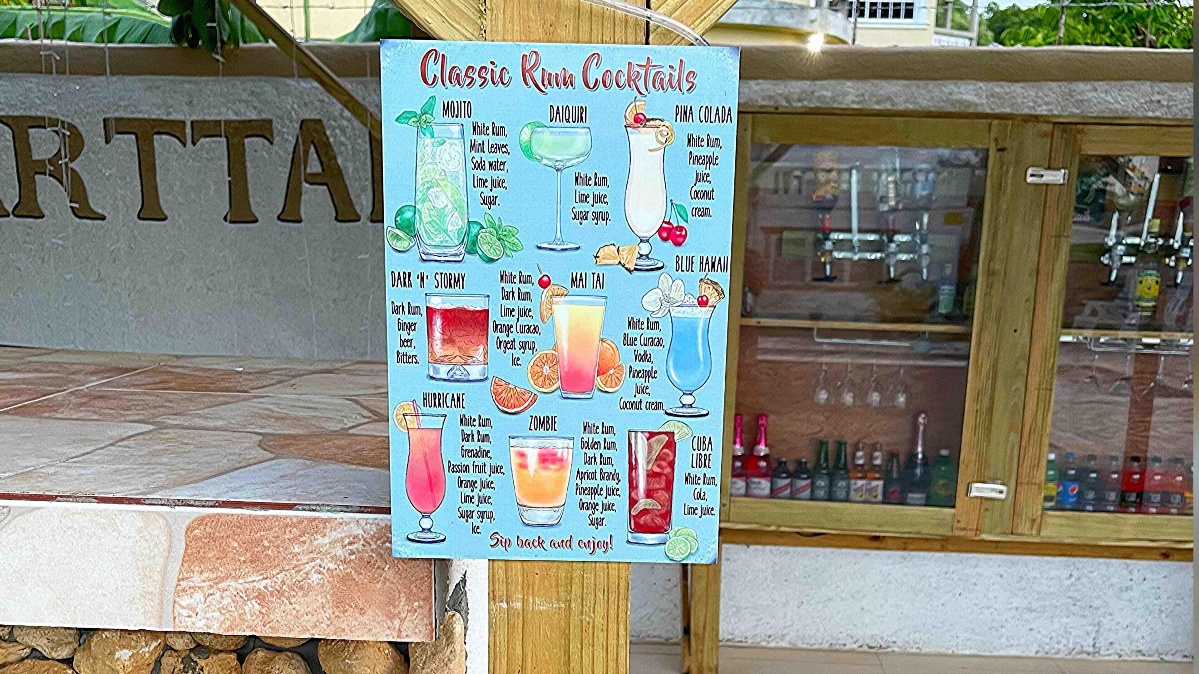 Een menubord met klassieke rumcocktails in een bar, met een betegelde vloer en een houten toonbank.