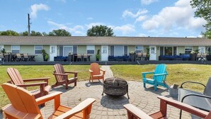 Un motel doté d’un espace extérieur aménagé avec des chaises Adirondack et un foyer.