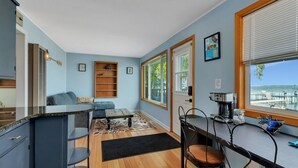 Un espace de vie compact comprenant un coin cuisine, une table à manger avec des chaises, un canapé et une machine à café.
