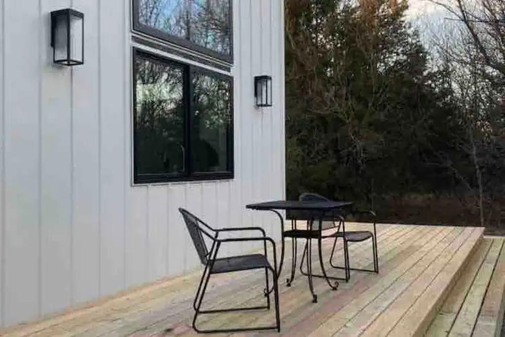 Een modern terras buiten met metalen meubilair en twee wandlampen.